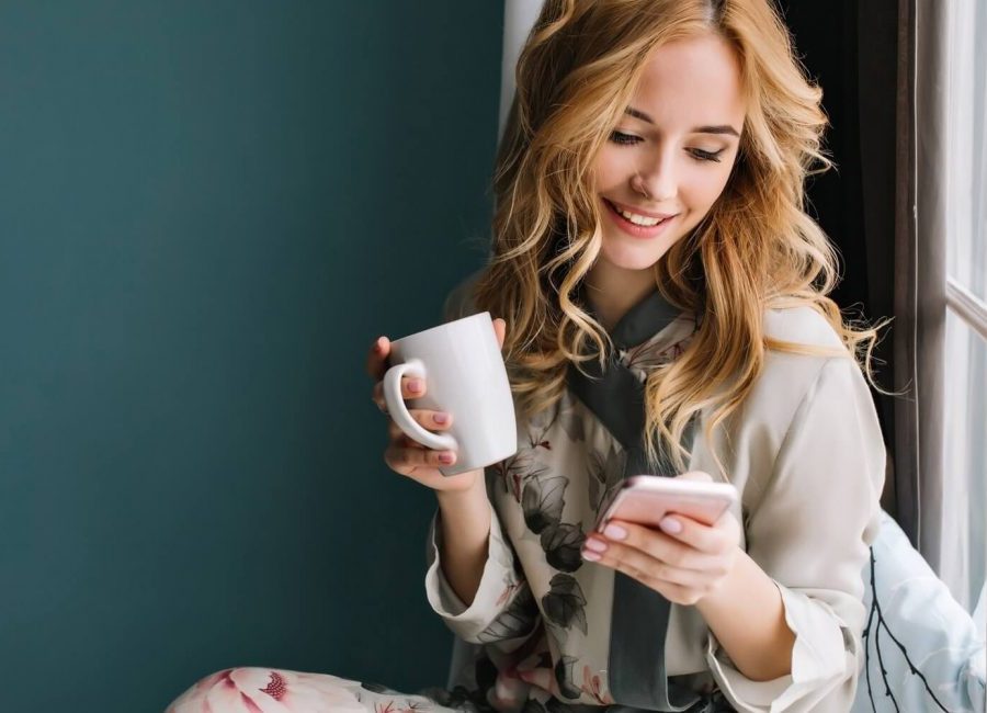 pretty-blonde-girl-sitting-window-sill-with-cup-1300x650